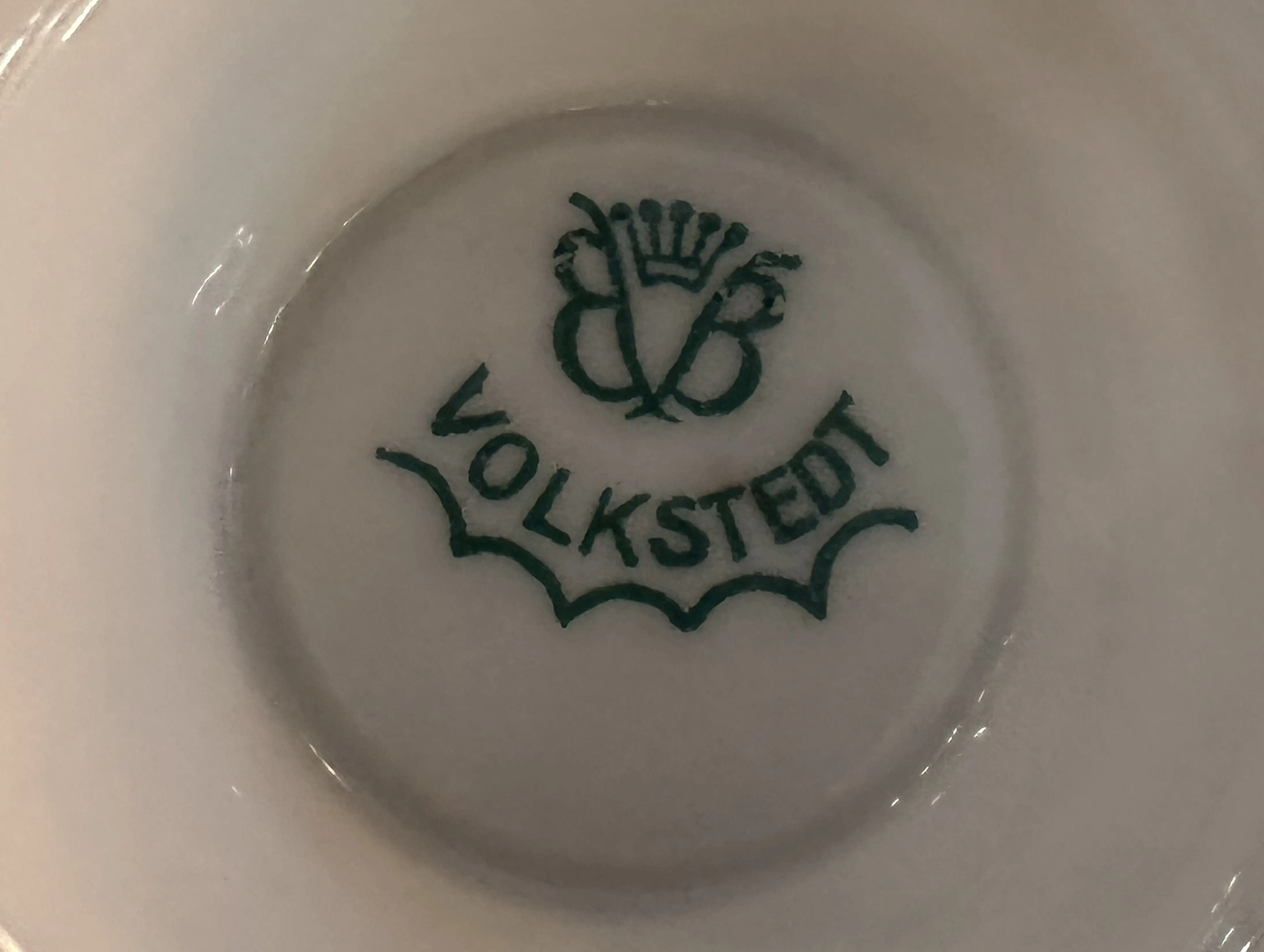 sello antiguo con letras verdes marcadas como VOLKSTEDT y un diseño decorativo.