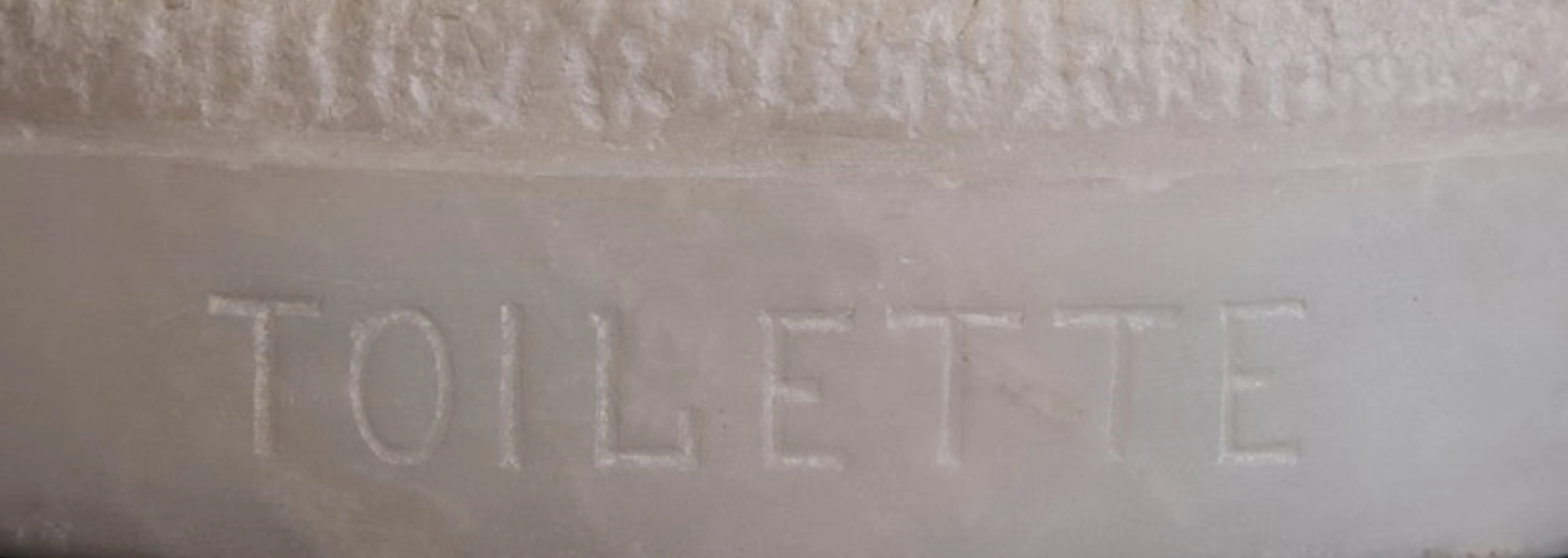 Sello antiguo con texto 'Toilette' en un diseño sencillo.